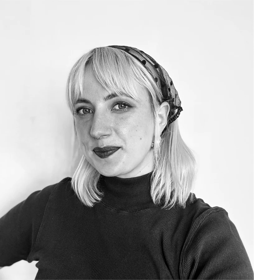Photo of Magdalena with blonde hair and bangs, wearing a headscarf and a dark turtleneck